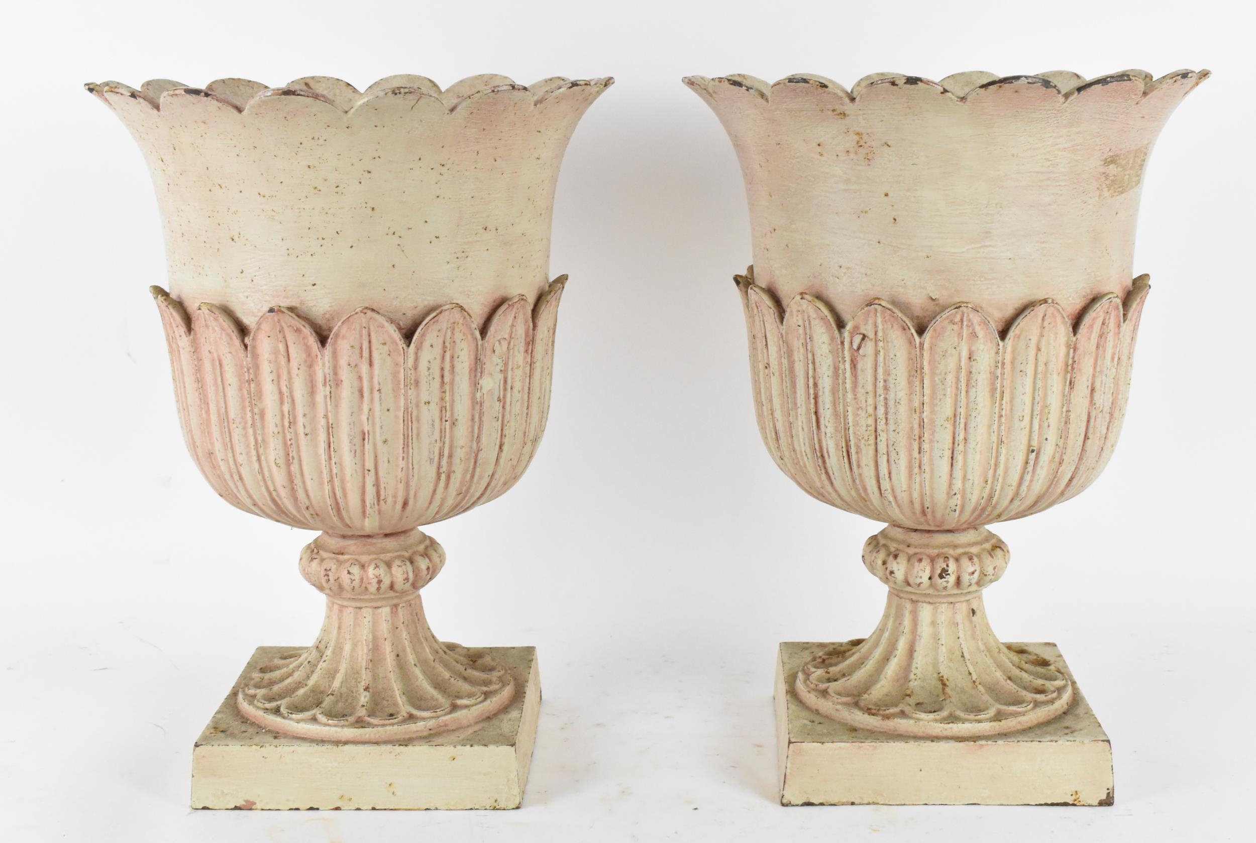 A pair of cast metal garden urns, with everted petal rim, part of the body with cast leaf, on a