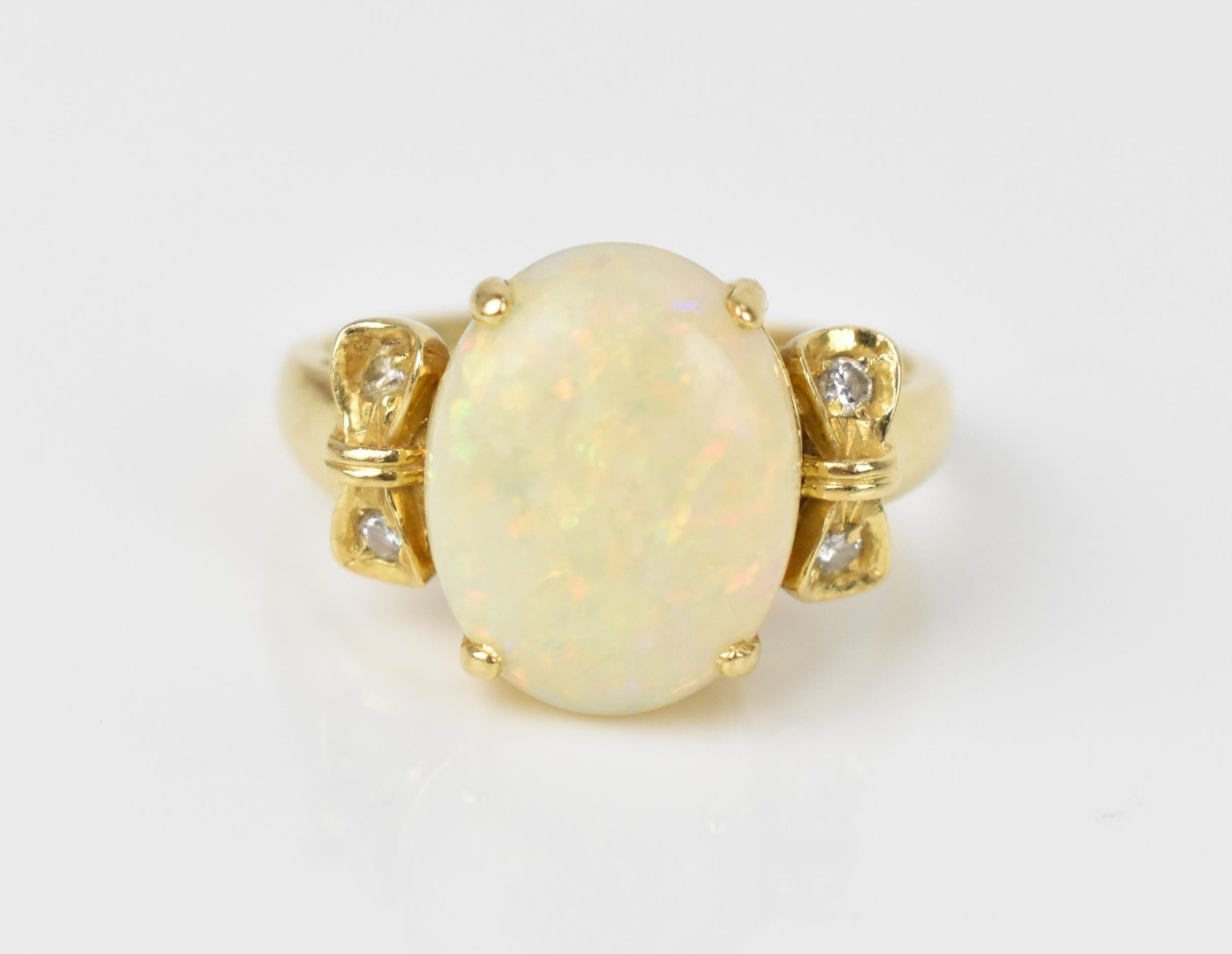 An 18ct yellow gold, opal and diamond dress ring, with central oval cabochon white opal flanked with