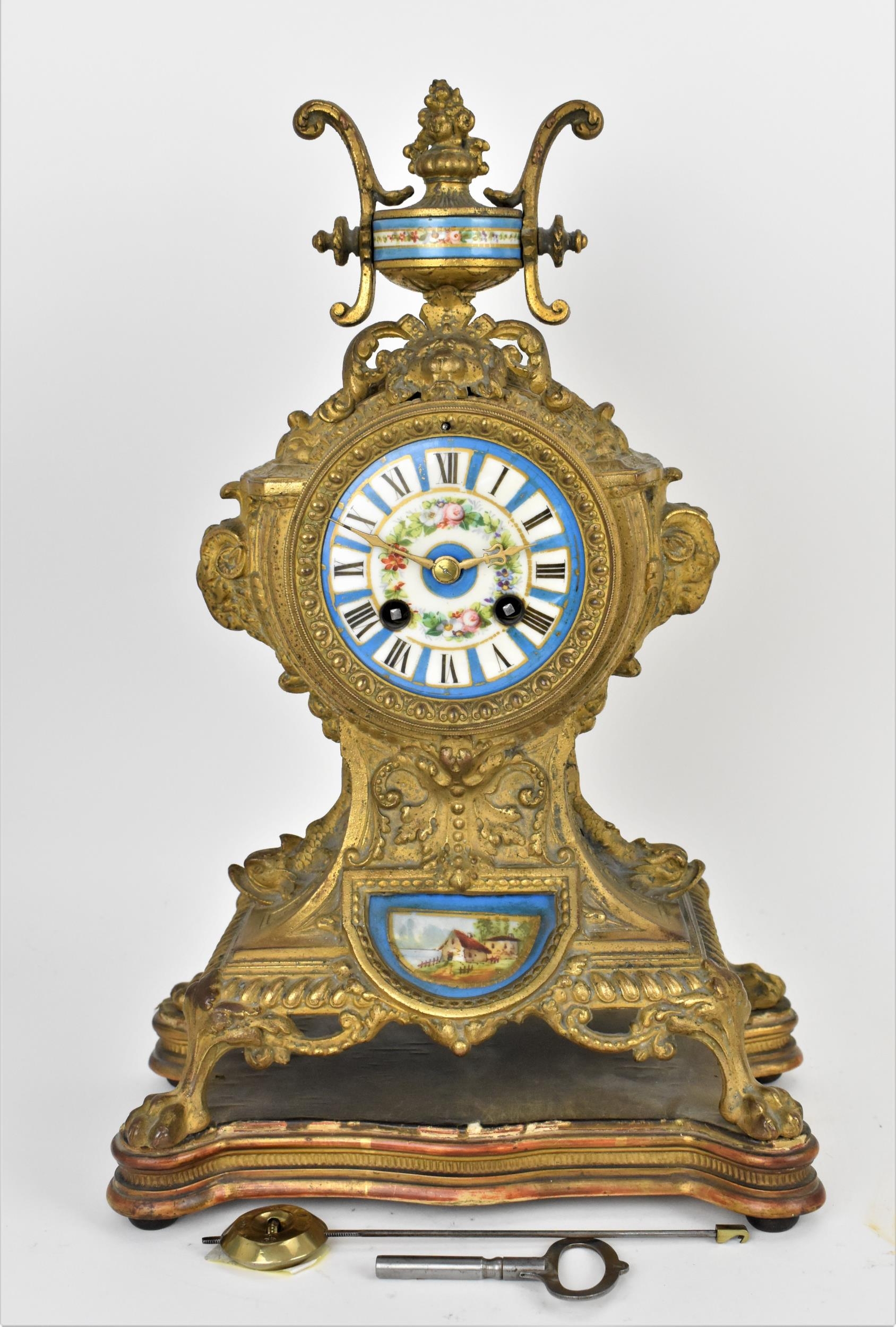 A 19th century French gilt metal mantle clock having a flower shaped finial on a twin handled urn