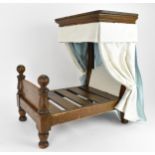 A 19th century doll's half tester bed, with upholstered bed hangings and headboard, on turned