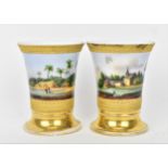 A pair of 19th century Biedermeier topographical cups, with gilt frieze of rings and leaf-tip