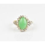 A 14ct yellow gold, diamond and green jade dress ring, with central oval cabochon jade in a halo