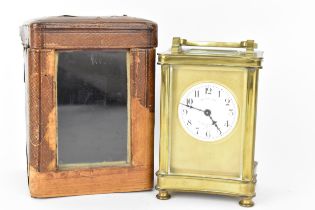 An early 20th century brass cased carriage clock in a fitted travel case having a white enamel