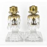 A pair of Regency style candlesticks, the cast palm leaf drip pan with hanging faceted glass pear