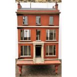 A large and impressive late Victorian townhouse doll's house, with red facade and slate roofing,
