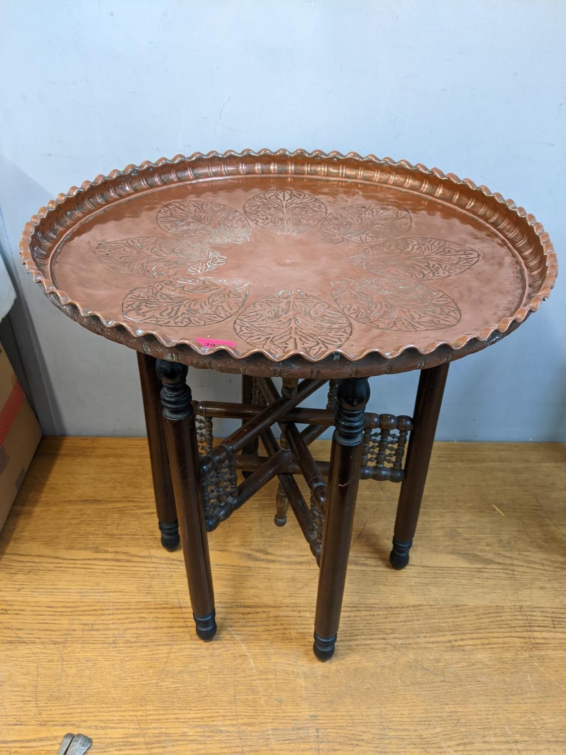 An Egyptian table with an embossed copper tray, on a folding stand, 63cm h, 60cm dia