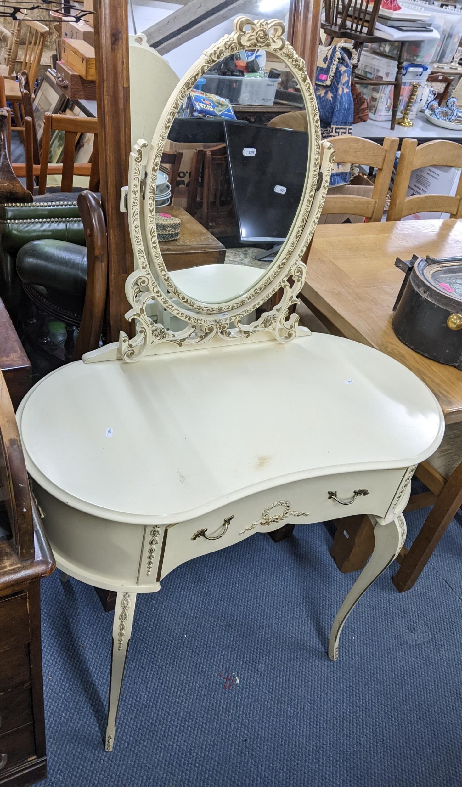 A mid 20th century French style cream painted dressing table with a swing mirror and on cabriole