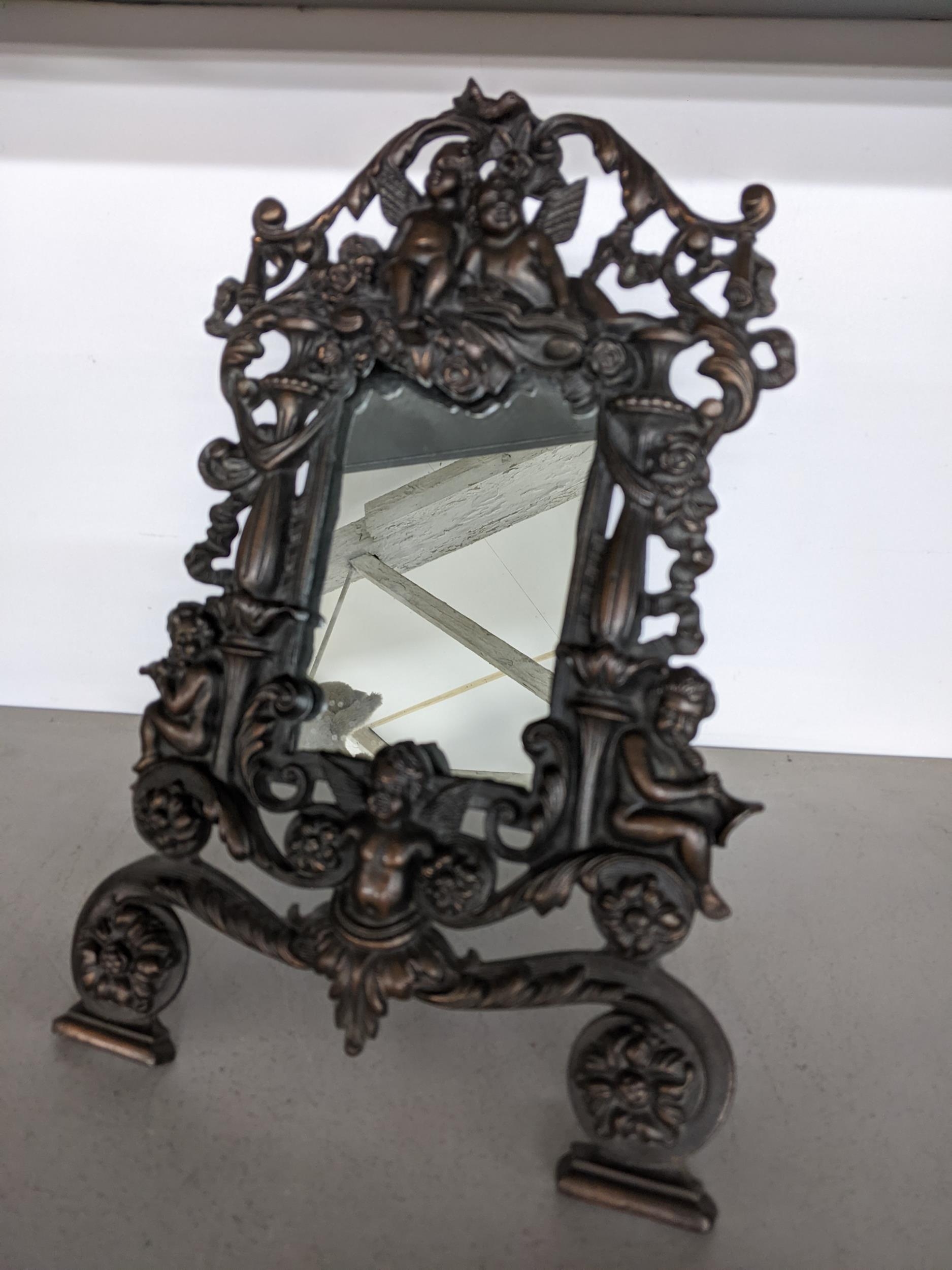 A small late 19th/early 20th century cast iron mirror with easel back, decorated with cherubs and