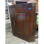 A Georgian oak wall hanging corner cabinet, panelled door with brass handle and lock plate, interior