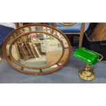 A 20th century oval gilt framed mirror and a brass desk lamp
