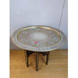 An Egyptian table with a copper, white metal and brass tray top, on a bone inlaid wooden folding