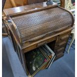 An early 20th century Waring & Gillows oak roll top desk having a fitted interior, one long and four