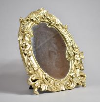 A Gilt Framed Oval Easel Back Mirror with Cherub Decoration, 30cm high