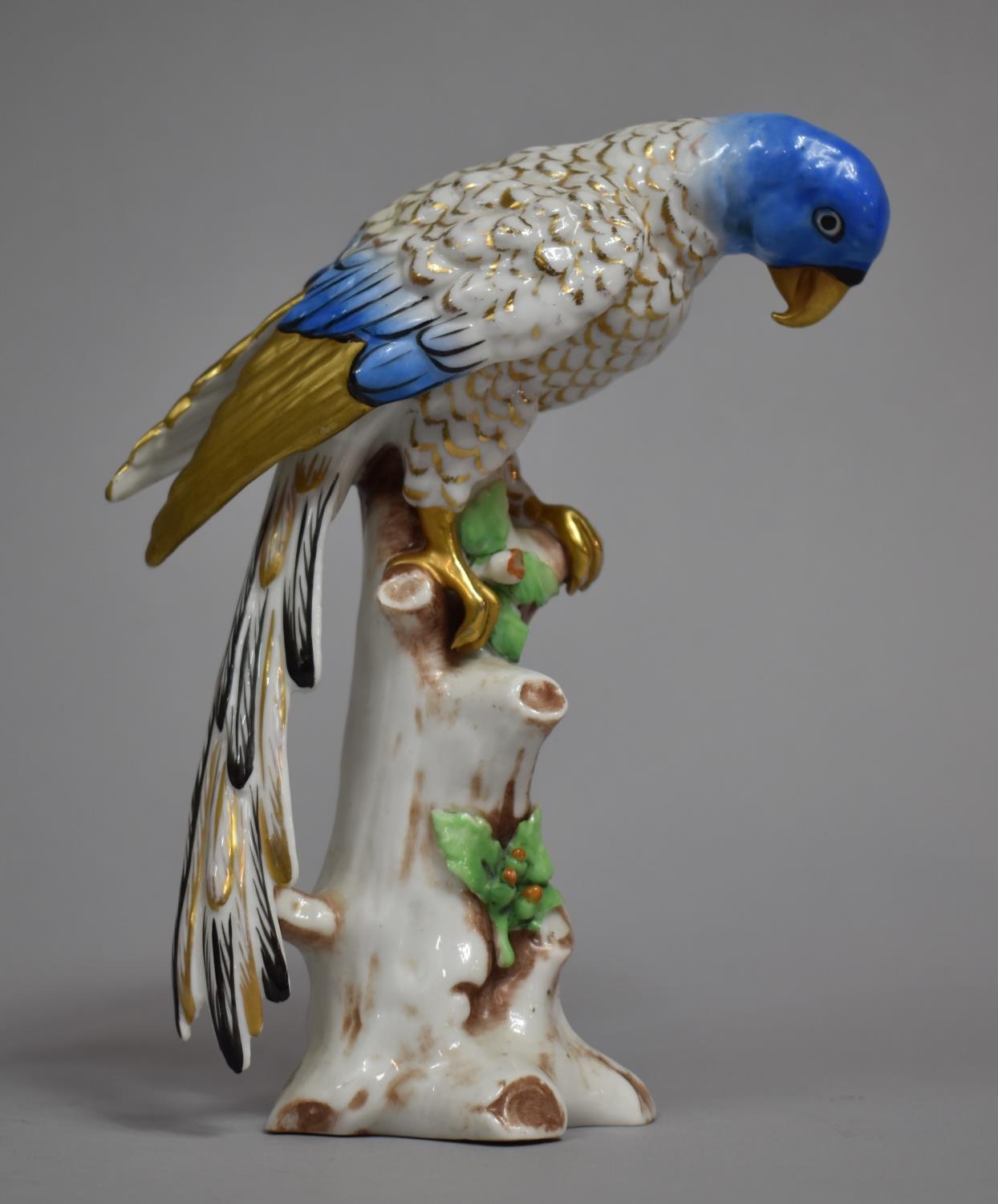 A Continental Porcelain Study of Blue Feathered Parrot on Branch Enriched with Gilt Highlights.