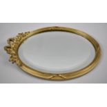 A Small Gilt Framed Oval Wall Mirror with Bevelled Glass and Ribbon and Swag Finial, 28cms High