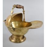 A Brass Helmet Shaped Coal Scuttle with Turned Wooden Handles, 45cms Long