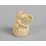 A Carved Bone Chinese Novelty in the form of a Monkey Holding Sack, 6cm high