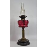 A Late Victorian Brass and Cranberry Glass Oil Lamp with Ribbed Column Support, Dual Controls, Glass