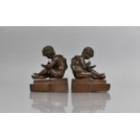 A Pair of French Bronze Bookends Modelled as Robed Classical Scribing Cherubs, 13cms high