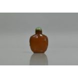 An Amber Glass Snuff Bottle with Carved Shoulders having Jade Stopper with Gold Band, 7cms High