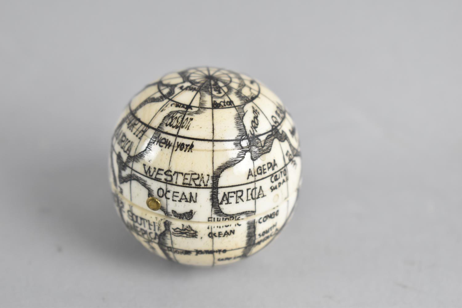 A Reproduction Scrimshaw Pocket Globe of Hinged Form with Inner Compass and Sundial, 4cms Diameter
