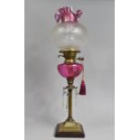 A Nice Quality Brass and Cranberry Glass Oil Lamp with Duplex Controls, Ribbed Column Support and