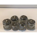 SIX HALLMARKED SILVER EMBOSSED TOP GLASS TOILET BOTTLES