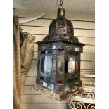 A MORROCAN STYLE HANGING METAL AND COLOURED GLASS LANTERN 30 X 70 CMS