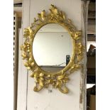 AN ORNATE OVAL GILT WALL MIRROR, 64 X 50CMS