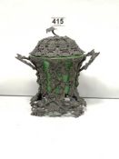 AN ORNATE GRAPE EMBOSSED SILVER PLATED LIDDED POT WITH TWO HANDLES AND GREEN GLASS LINER, 17CMS