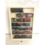 A QUANTITY OF MODEL VEHICLES IN A WALL MOUNTED DISPLAY CABINET