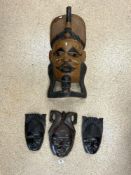 A LARGE CURVED INDONESIAN WOODEN WALL MASK AND THREE SMALLER CARVED HARDWOOD WALL MASKS, THE LARGEST