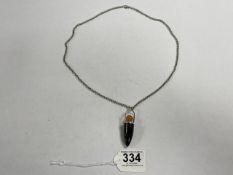 A BULLET-SHAPED BLACK STONE AND AMBER PENDANT ON CHAIN