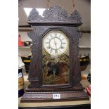AN AMERICAN MANTLE CLOCK IN A CARVED FRAME WITH BIRD DECORATION TO GLASS CHIMING WATERBURY CLOCK