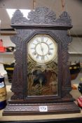 AN AMERICAN MANTLE CLOCK IN A CARVED FRAME WITH BIRD DECORATION TO GLASS CHIMING WATERBURY CLOCK