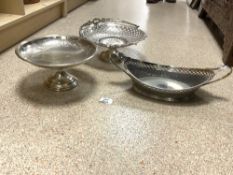 A SILVER-PLATED PIERCED SWING HANDLE CAKE BASKET, A BOAT SHAPED DISH AND A COMPORT