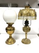 AN ORNATE EMBOSSED BRASS OIL LAMP (CONVERTED TO ELECTRIC), SHADE HAVING COLOURED STONES INSET AND