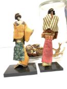 TWO JAPANESE FIGURES IN DRESS UNDER A CYLINDRICAL GLASS CASE, 38CMS