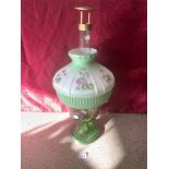 A LATE VICTORIAN GREEN GLASS OIL LAMP WITH BRASS FIXTURES AND WITH A FLORAL DECORATED OPAQUE GLASS