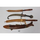 EASTERN KNIFE & FORK IN A CARVED WOODEN FISH SHAPE SCABBARD, EASTERN KNIFE IN METAL SHEAF AND TWO