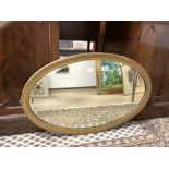 A 1930S OVAL GILT FRAMED WALL MIRROR, 83 X 54CMS