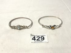 TWO HALLMARKED SILVER BANGLES, ONE SET IN BLUESTONE AND THE OTHER A YELLOW/ORANGE STONE, TOTAL