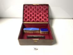 TWO HALLMARKED SILVER AND ENAMEL BRUSHES, A SILVER MOUNTED COMB IN A TOOLED LEATHER BOX