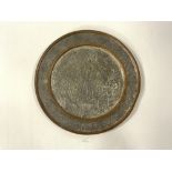 AN EASTERN COPPER AND WHITE METAL CIRCULAR WALL PLAQUE WITH EMBOSSED PEACOCK AND CRANE FLORAL