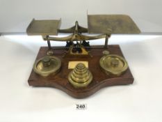 A LARGE SET OF LATE VICTORIAN BRASS LETTER AND PARCEL SCALES ON OAK BASE WITH WEIGHTS