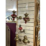 A PAIR OF VICTORIAN BRASS WALL MOUNTED OIL LAMPS WITH RUBY GLASS FONTS, A SMALLER WALL MOUNTED BRASS