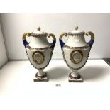 A PAIR OF 20TH CENTURY FRENCH CERAMIC TWO HANDLED MANTLE URNS WITH LIDS, ON SQUARE PLATFORM BASES,