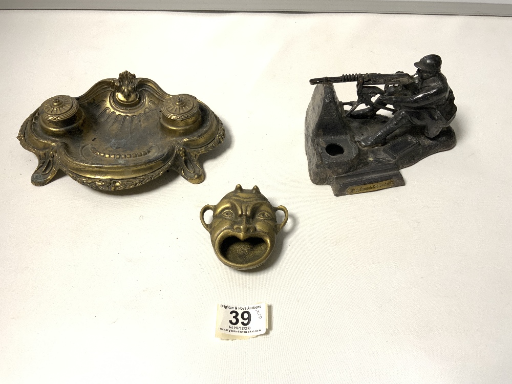 ORNATE BRASS DOUBLE INKSTAND, A BRASS DEVIL ASHTRAY, AND A SPELTER MODEL OF A FRENCH MACHINE