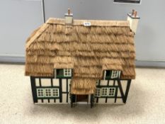 A TUDOR STYLE DOLLS HOUSE WITH THATCHED ROOF AND CONTAINS FURNITURE, FIGURES, FIXTURES & FITTINGS