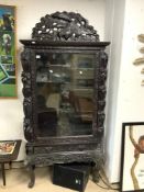 A LATE 19TH CENTURY/EARLY 20TH CENTURY ORIENTAL BLACK CARVED DISPLAY CABINET WITH EXOTIC BIRD, A